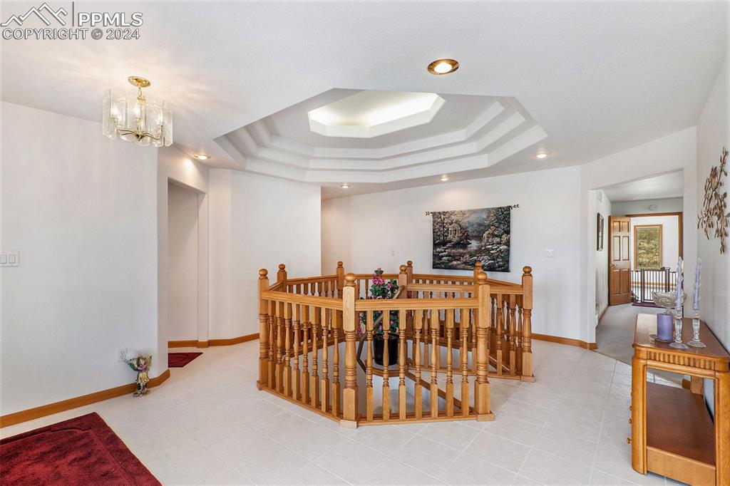 Image 17 of 50: Dining room featuring a chandelier, a raised ceiling, and light tile floors
