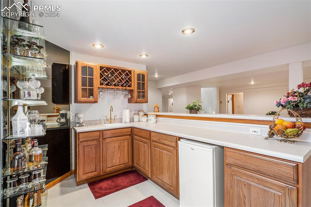 Image 34 of 50: Wet Bar with fridge, light tile floors, peninsula, and sink