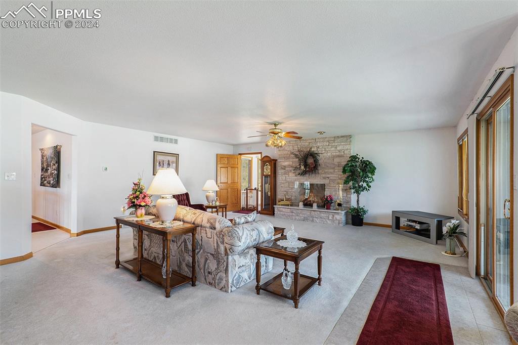 Image 9 of 50: Living room with plenty of natural light and a stone fireplace.