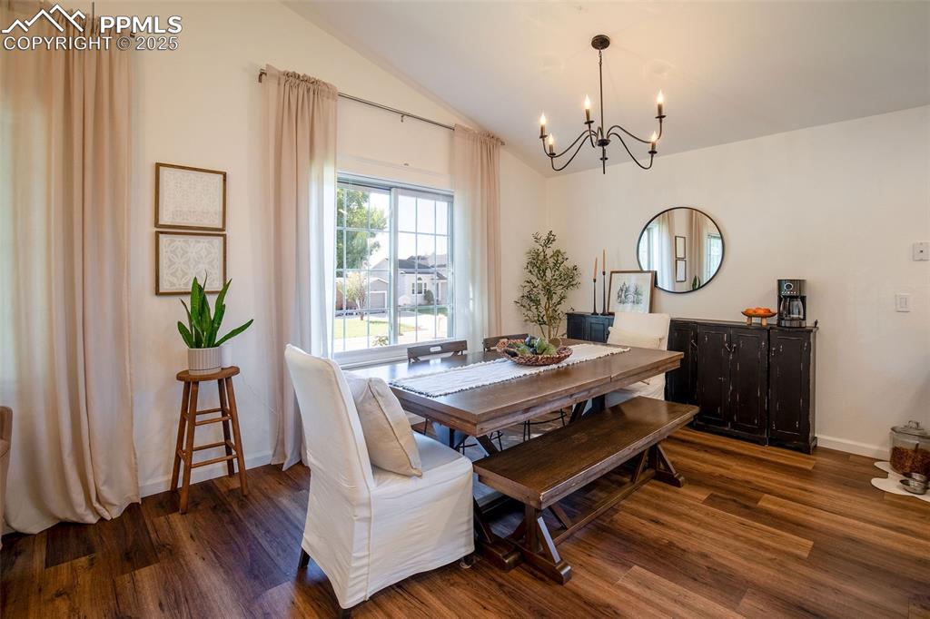 Image 10 of 41: Dining space featuring lofted ceiling, dark wood-type flooring, and a chand
