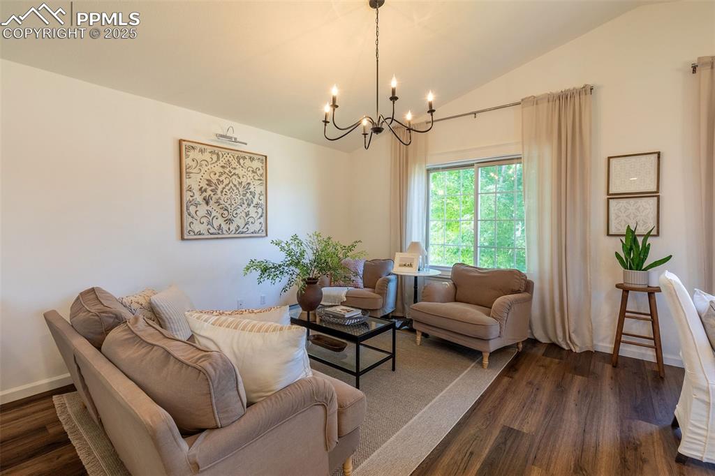 Image 14 of 41: Living area with dark wood-style floors, a chandelier, and lofted ceiling