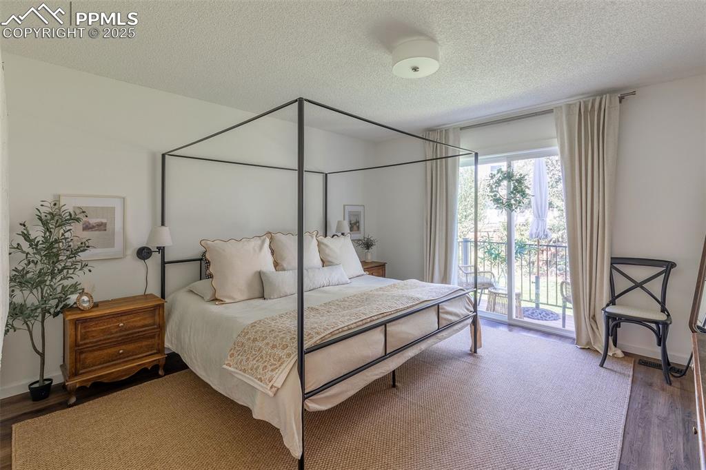 Image 21 of 41: Bedroom with wood finished floors, a textured ceiling, and access to exteri