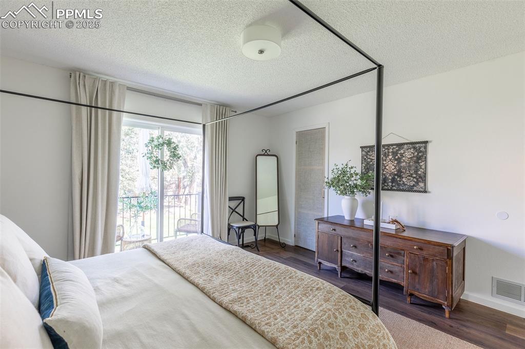 Image 23 of 41: Bedroom with a textured ceiling, dark wood-type flooring, and access to ext