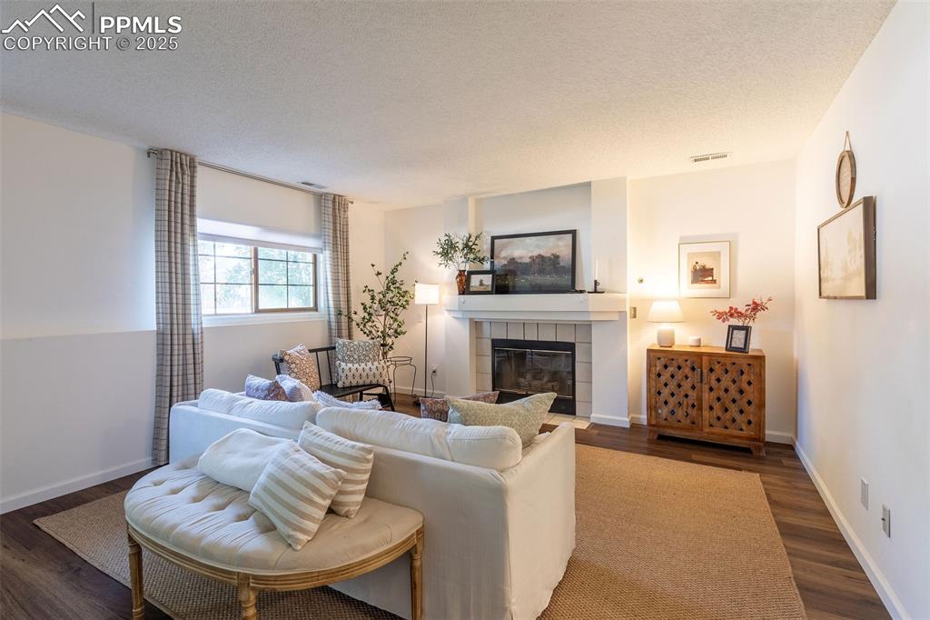 Image 24 of 41: Living area with a textured ceiling, a tile fireplace, and dark wood-style 