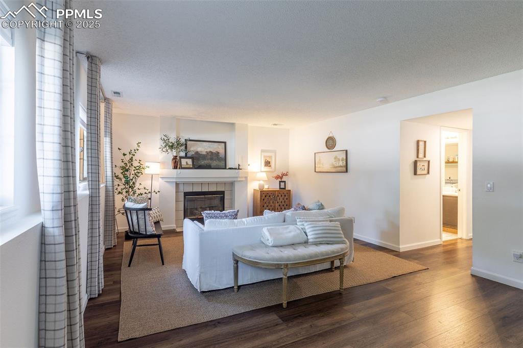 Image 26 of 41: Living room featuring dark wood finished floors and a tiled fireplace