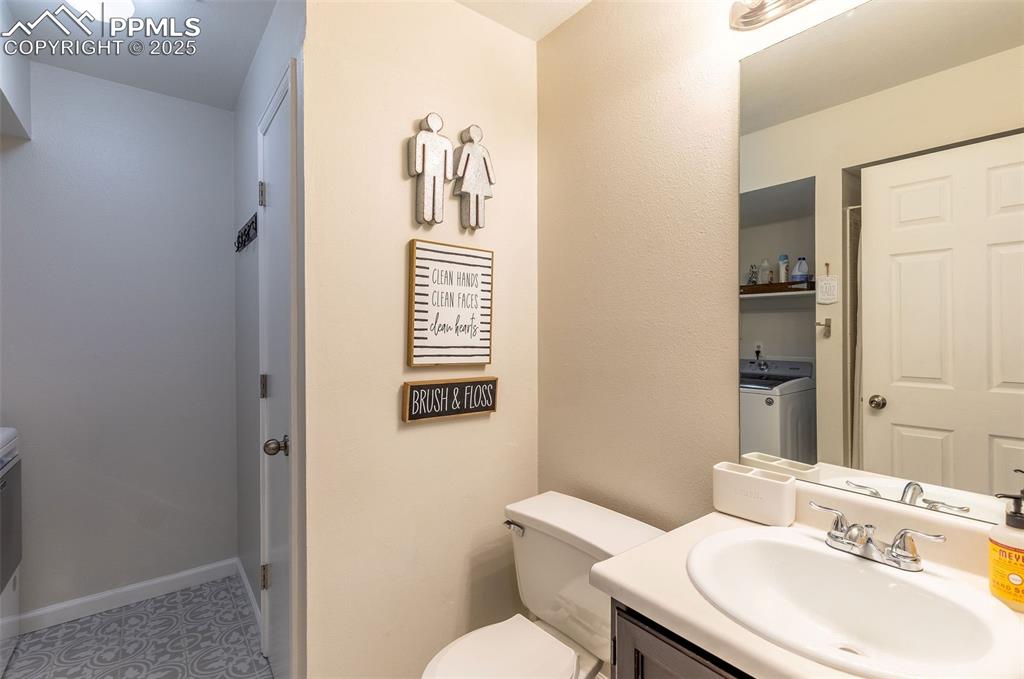 Image 27 of 41: Bathroom featuring washing machine and clothes dryer, vanity, and light til