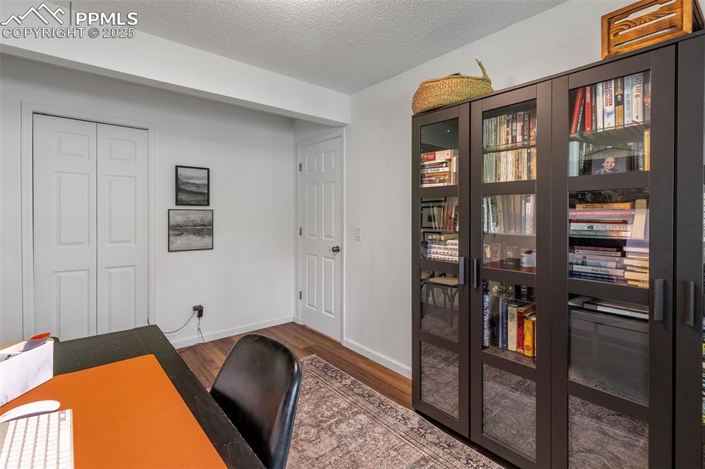 Image 31 of 41: Office space with a textured ceiling and dark wood-style flooring