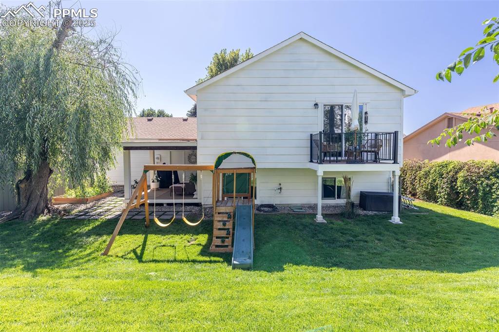 Image 39 of 41: Rear view of house featuring a playground, a deck, and a lawn