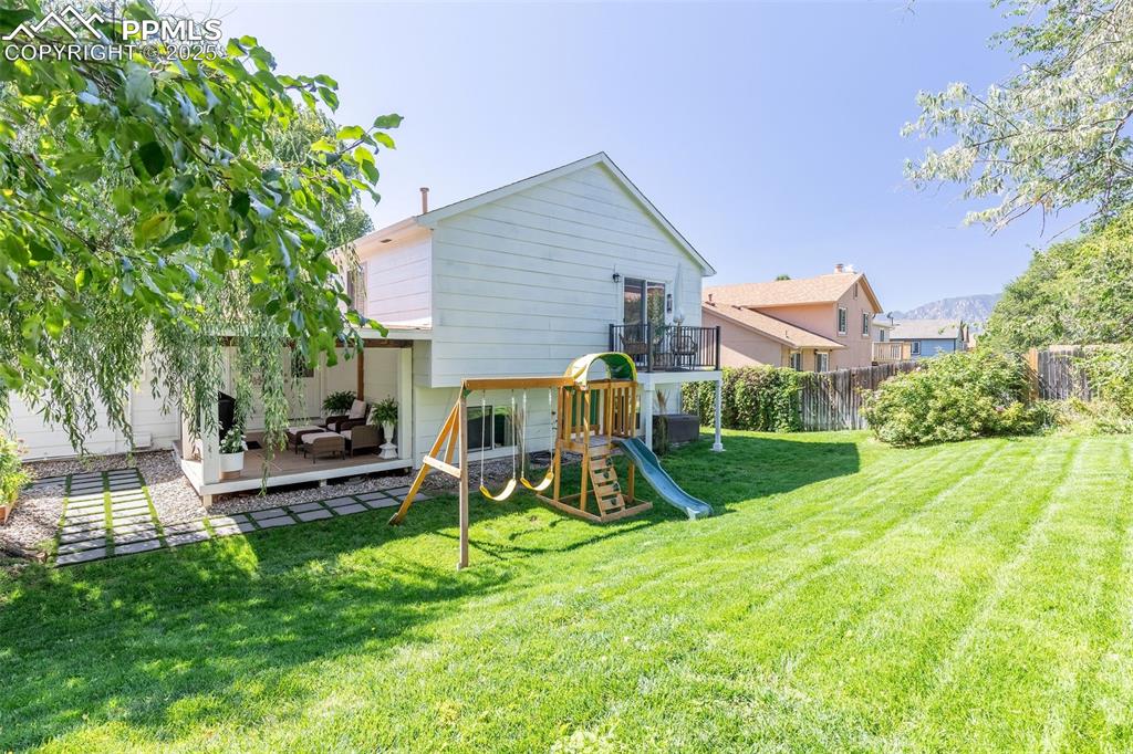 Image 40 of 41: Back of property with a playground, an outdoor living space, and a patio
