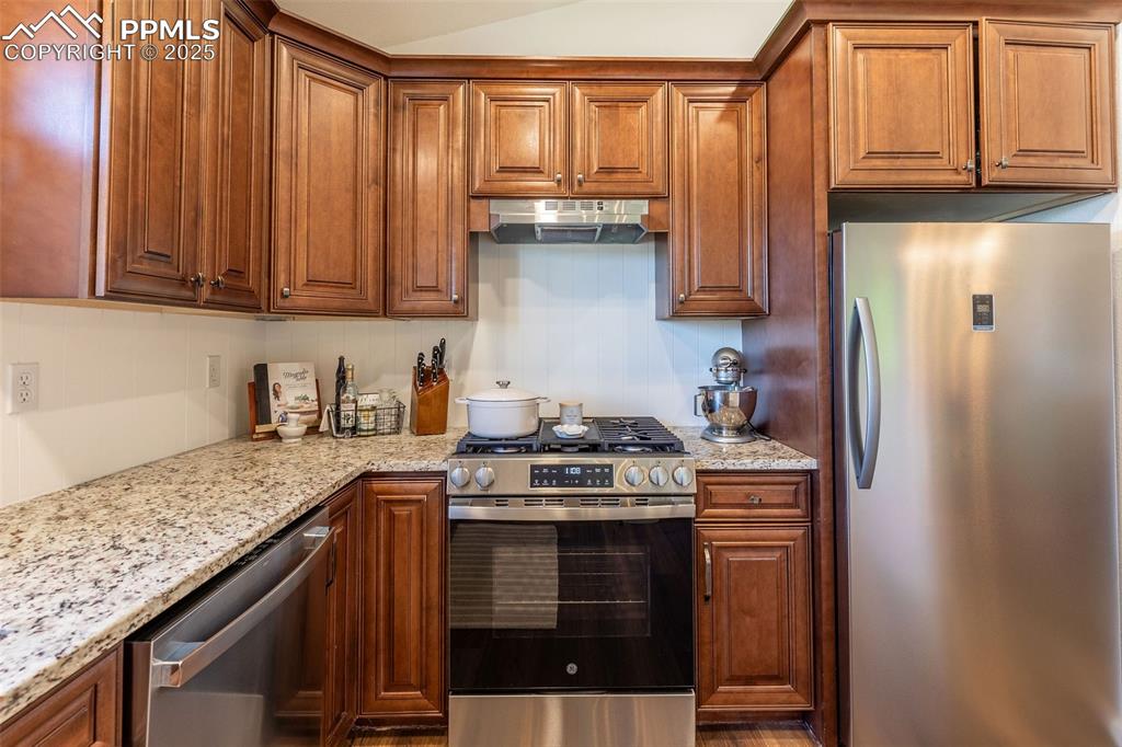 Image 8 of 41: Kitchen featuring appliances with stainless steel finishes, light stone cou