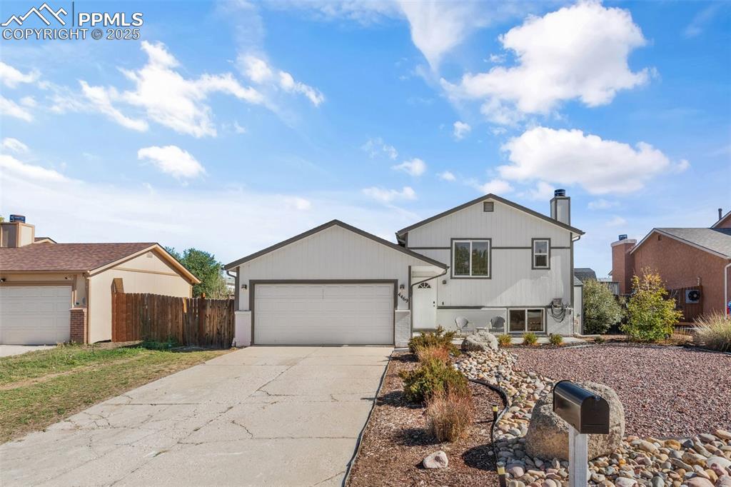 Caption: Bi-level home with concrete driveway, a chimney, and a garage