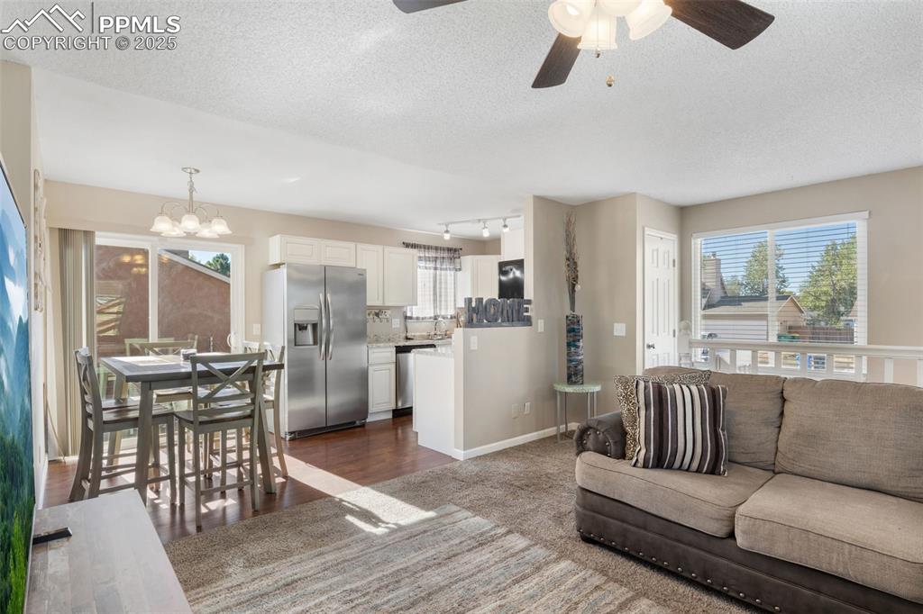 Image 10 of 38: Living area with a textured ceiling, dark wood-style floors, and a chandeli
