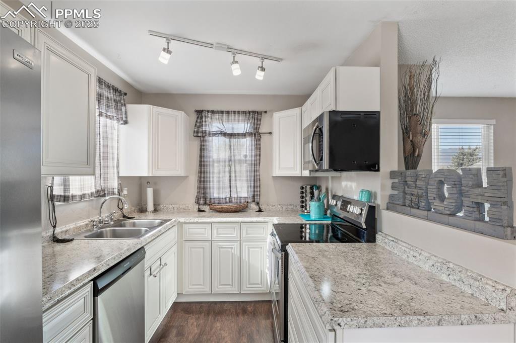 Image 12 of 38: Kitchen featuring stainless steel appliances, light countertops, dark wood-