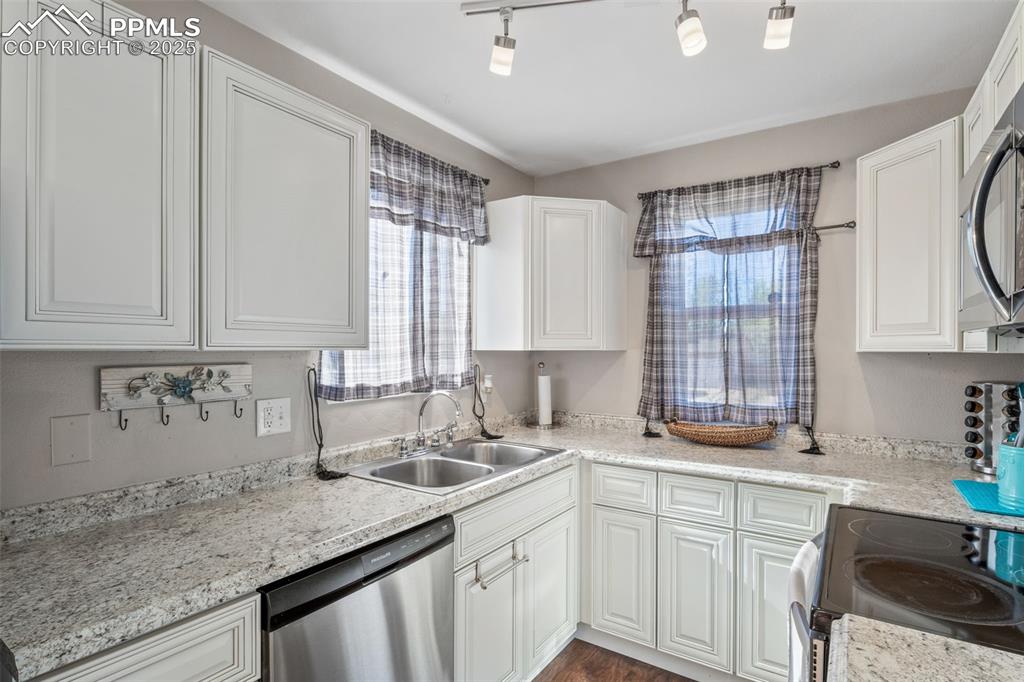 Image 13 of 38: Kitchen featuring stainless steel appliances, white cabinetry, and dark woo