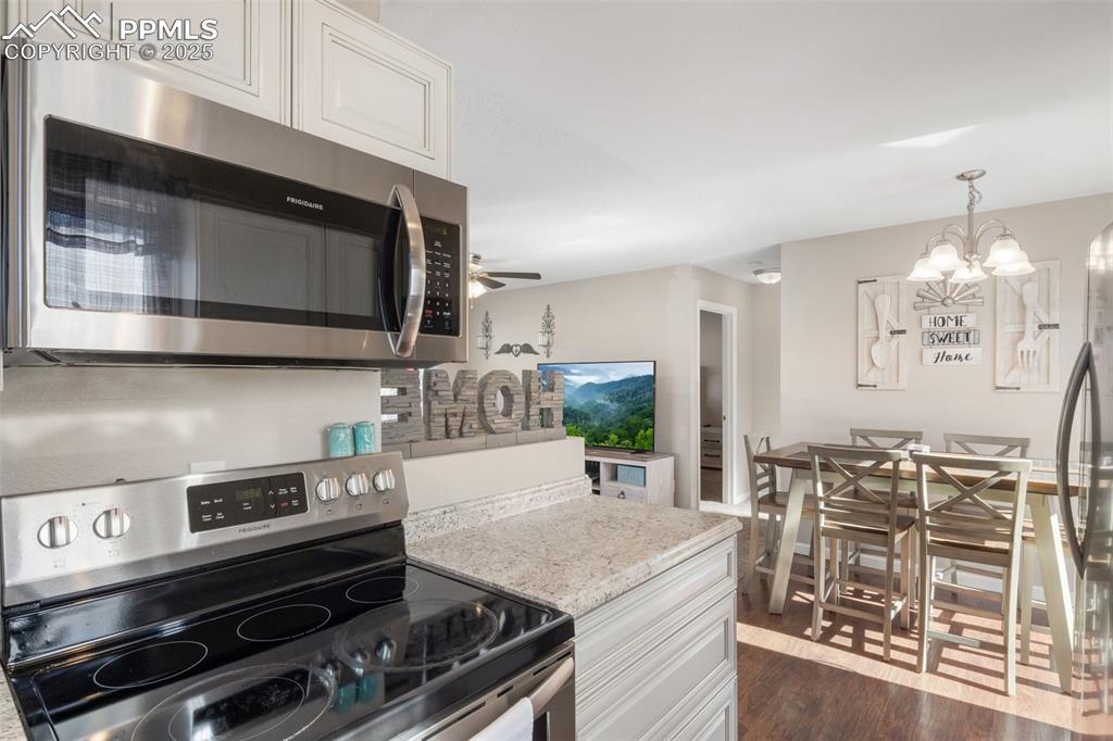 Image 14 of 38: Kitchen with appliances with stainless steel finishes, white cabinets, dark