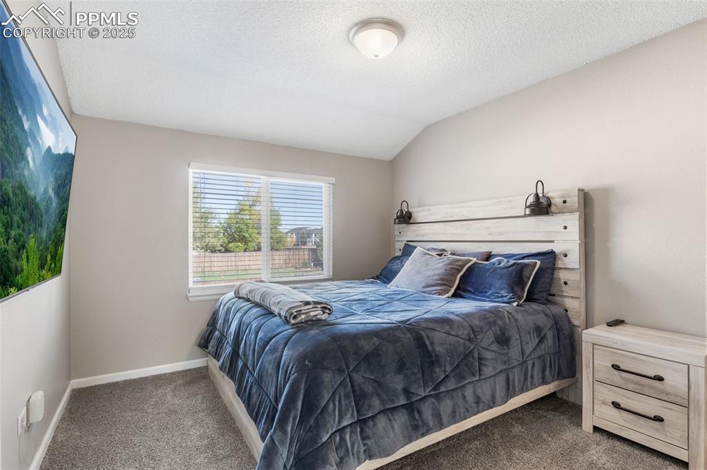 Image 15 of 38: Carpeted bedroom featuring lofted ceiling and a textured ceiling