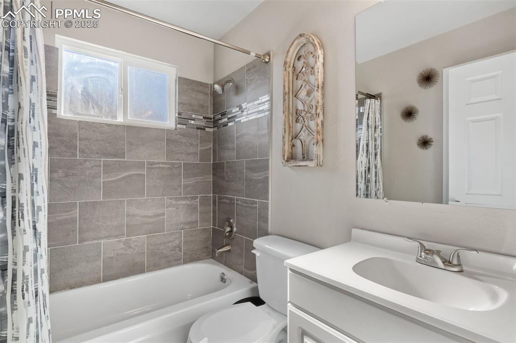 Image 18 of 38: Bathroom with shower / tub combo with curtain and vanity