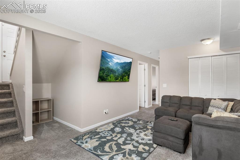 Image 19 of 38: Living room with stairs, carpet floors, and a textured ceiling