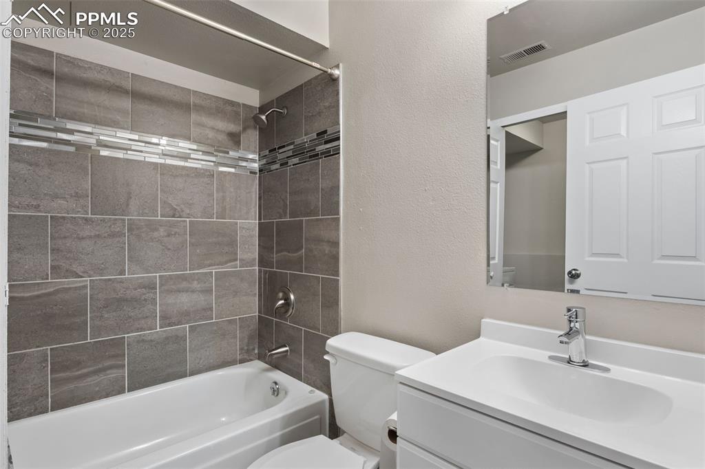 Image 25 of 38: Bathroom featuring shower / tub combination, vanity, and a textured wall