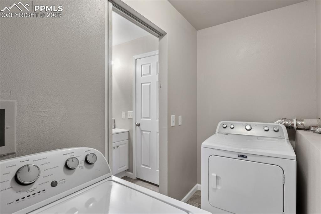 Image 28 of 38: Washroom with a textured wall and washer and dryer