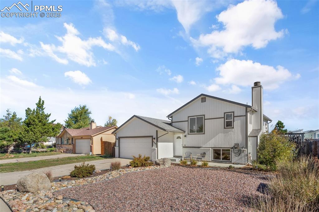 Image 3 of 38: View of front facade with concrete driveway, a chimney, and an attached gar