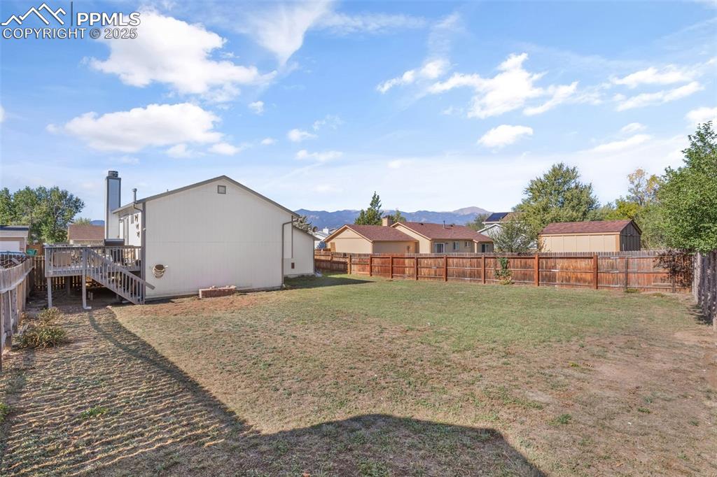 Image 31 of 38: Fenced backyard featuring a wooden deck, and stairway