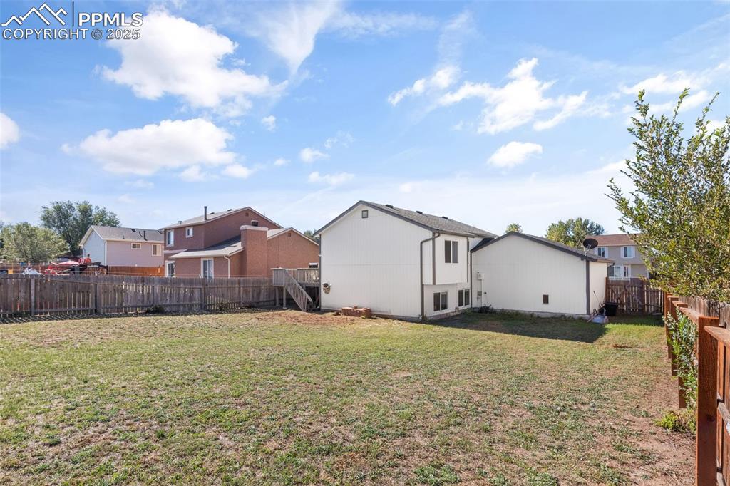 Image 32 of 38: Rear view of house with a fenced backyard and sideyard