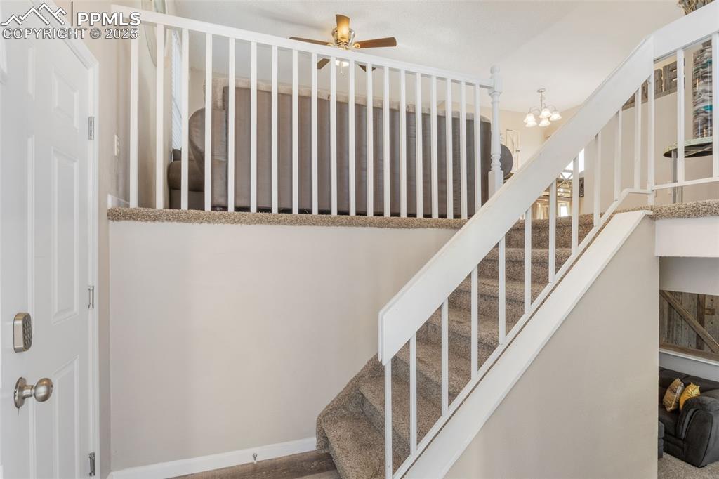 Image 5 of 38: Stairway with a chandelier and a ceiling fan