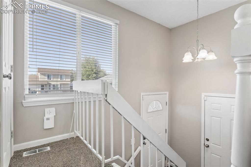 Image 6 of 38: Stairs with a chandelier and carpet floors