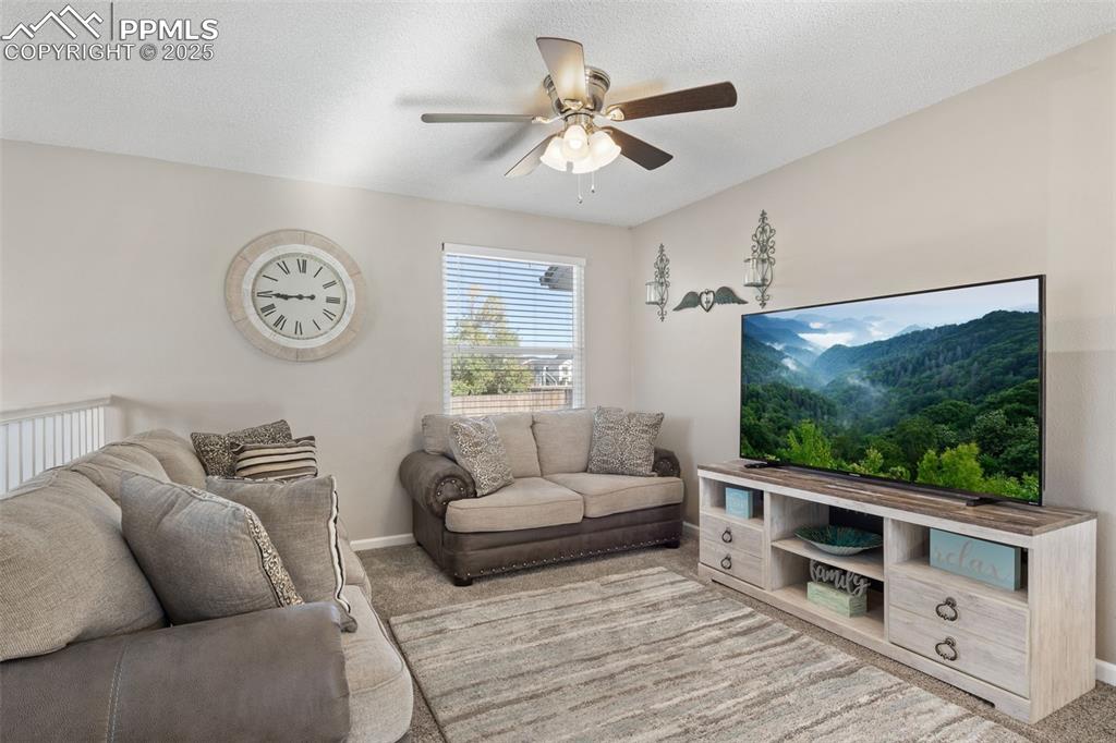 Image 8 of 38: Carpeted living room with a textured ceiling and ceiling fan