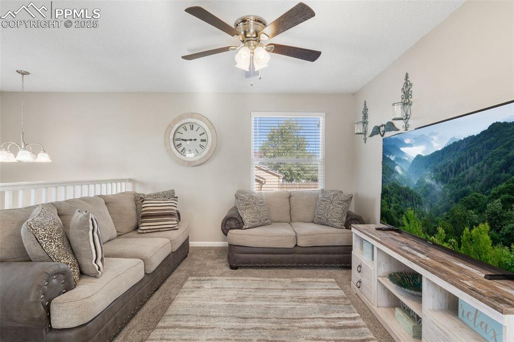 Image 9 of 38: Carpeted living area featuring ceiling fan and a chandelier