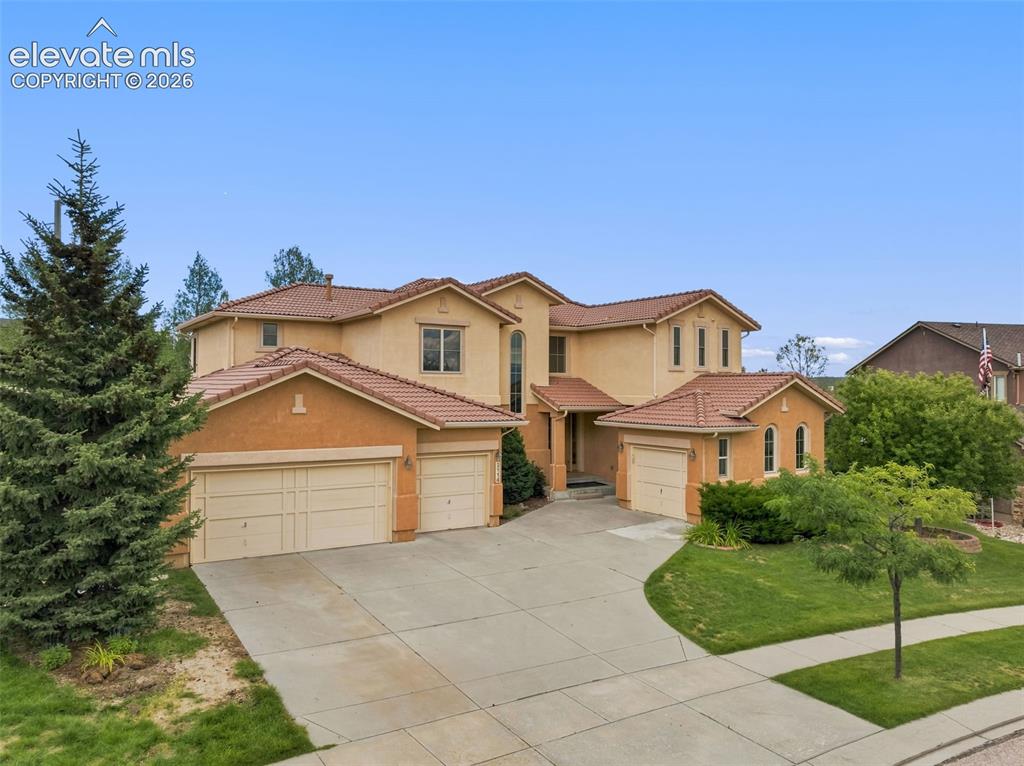 Caption: Stucco exterior featuring 4 attached garages, a tiled roof, and a concrete driveway