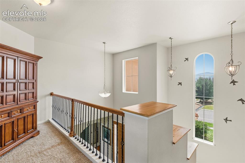 Image 20 of 47: Upper-level landing featuring a wrought iron and wood-finish railing, arche