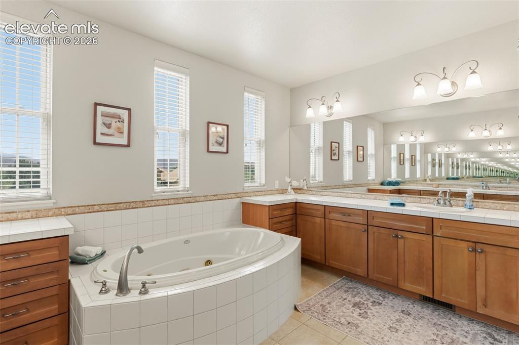 Image 25 of 47: Spacious bathroom featuring an oval JACUZZI soaking tub with tile surround,
