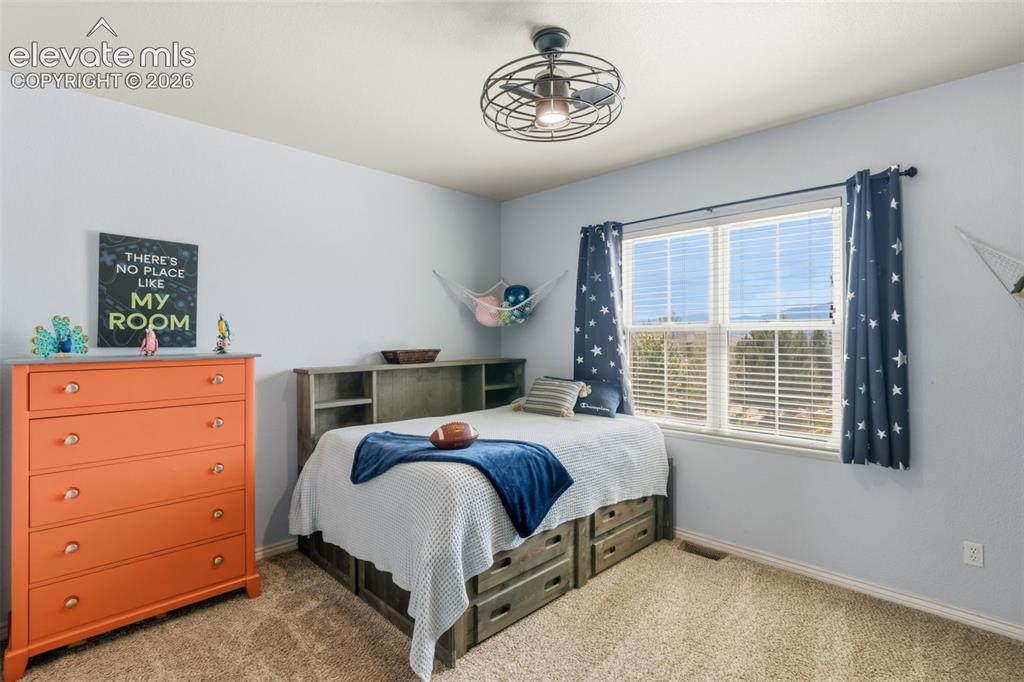 Image 27 of 47: Spacious room featuring a large window, carpet flooring, a ceiling fan with