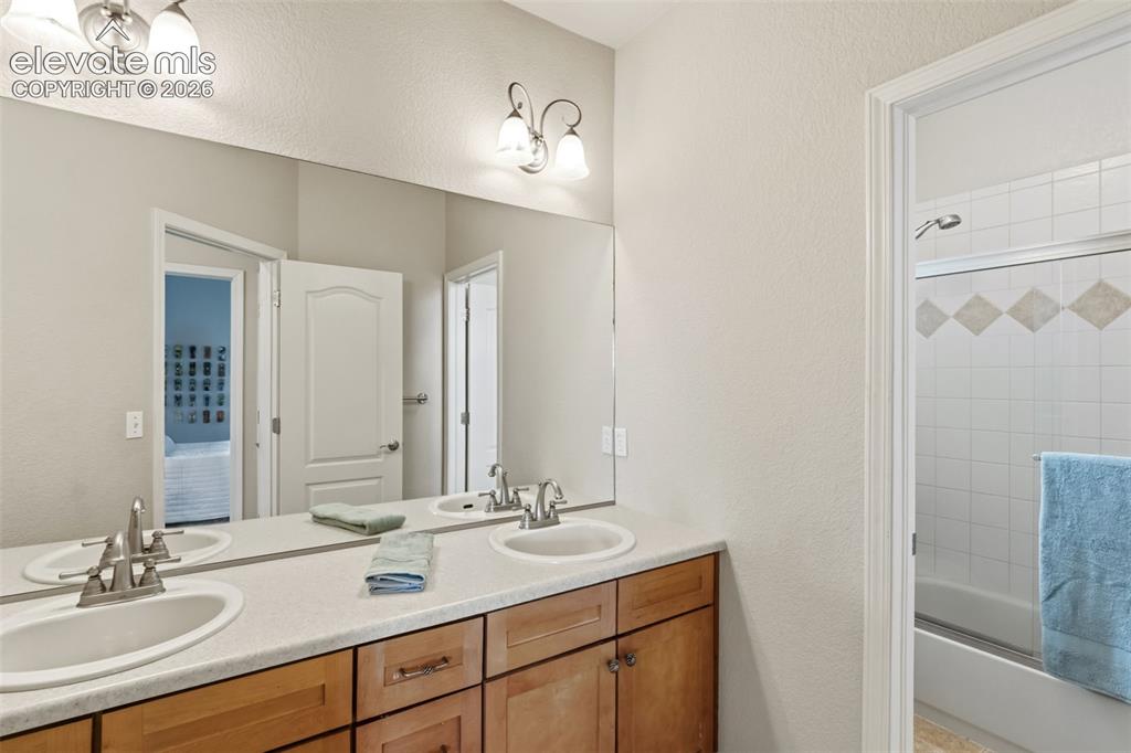 Image 29 of 47: Bathroom featuring a dual vanity with wood-finish cabinetry, a large wall-m
