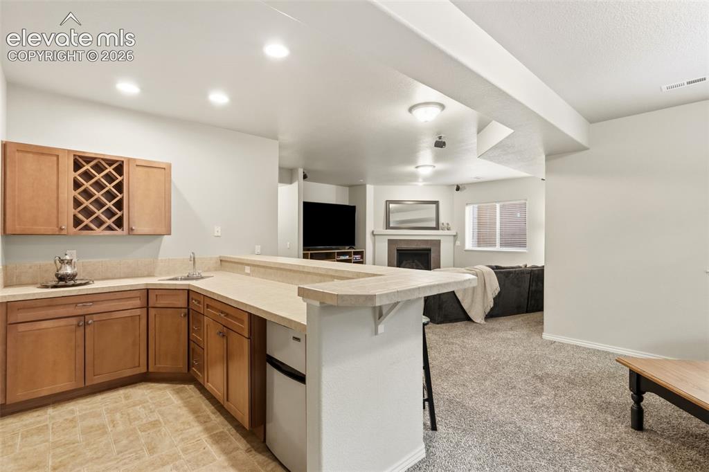 Image 33 of 47: Kitchenette featuring wood cabinetry with a built-in wine rack, light-toned
