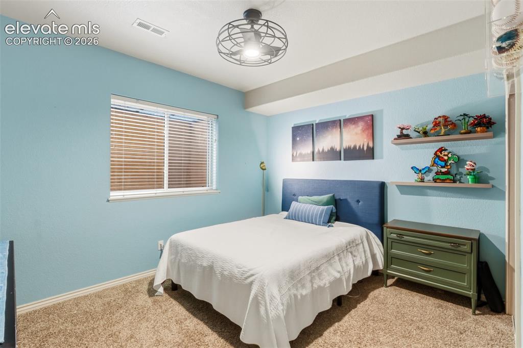 Image 35 of 47: Bedroom featuring textured blue walls, light-toned carpeting, and a white c