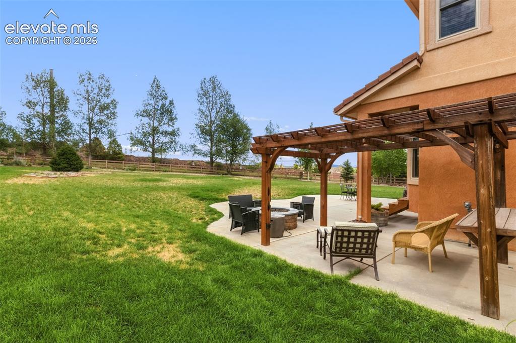 Image 41 of 47: Spacious stucco exterior featuring a concrete patio with a wooden pergola, 