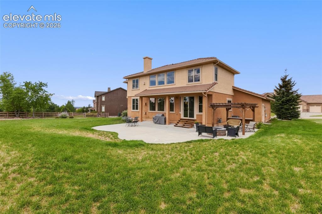 Image 42 of 47: Expansive backyard featuring a large concrete patio with a wooden pergola, 