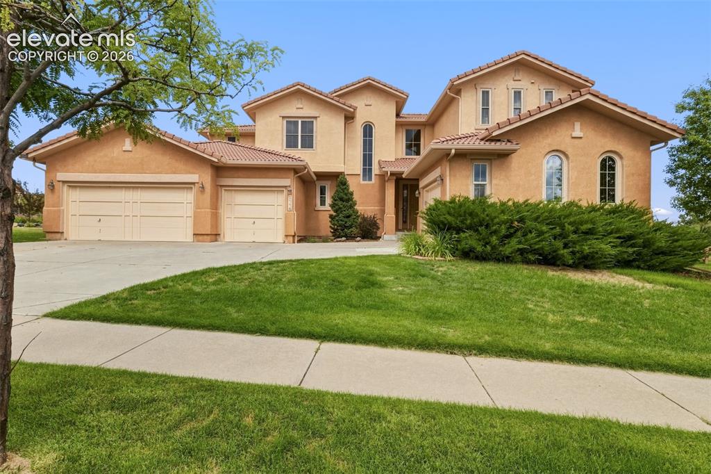 Image 6 of 47: Stucco exterior featuring multiple arched windows, a multi-car garage, and 