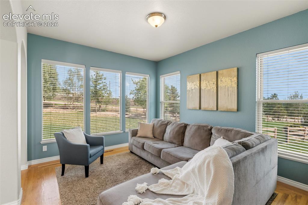 Image 9 of 47: Bright living area featuring multiple large windows with horizontal blinds,