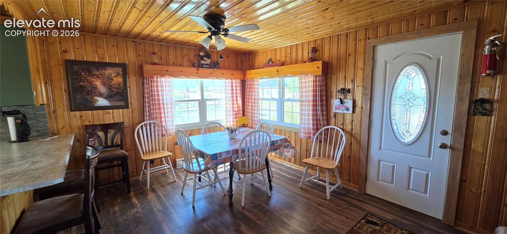 Image 11 of 35: Wood-paneled walls and ceiling, wood-finish flooring, two large windows, wh
