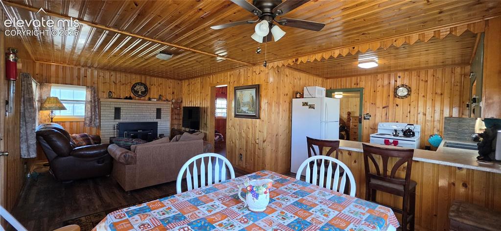 Image 12 of 35: Wood-paneled interior featuring a brick fireplace, wood-finish flooring, an