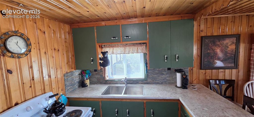 Image 13 of 35: Wood-paneled walls and ceiling, green cabinetry, laminate countertops, and 