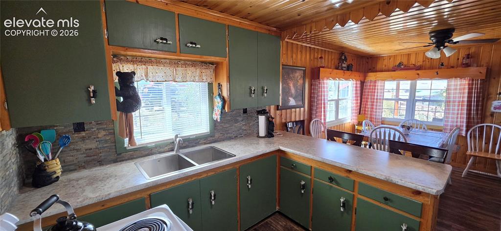 Image 14 of 35: Kitchen featuring wood-paneled walls and ceiling, green cabinetry, and a du