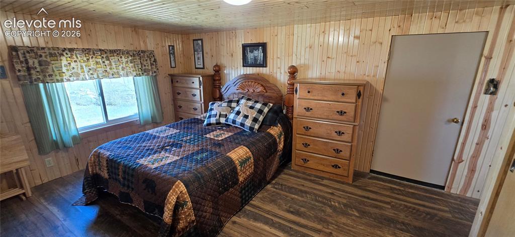 Image 16 of 35: Wood-finish flooring, paneled wood walls, and a single window with a valanc