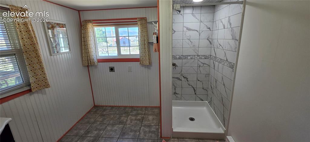 Image 19 of 35: Tiled shower with a white basin