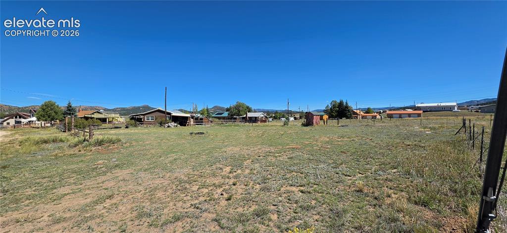 Image 29 of 35: Expansive open field with natural ground cover, partial fencing, and distan