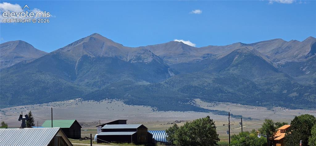 Image 35 of 35: Expansive mountain range backdrop with distant foothills, scattered trees, 